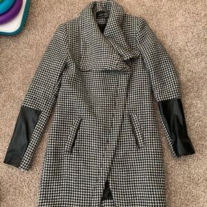 Black and white checkered winter jacket with leather sleeves.